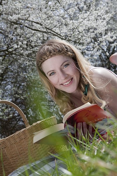 Blonde Frau liest auf der Wiese