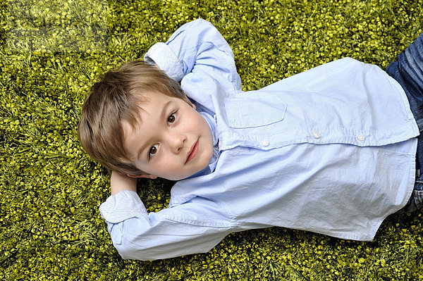 Junge  4 Jahre  liegt auf einem grünen Teppich