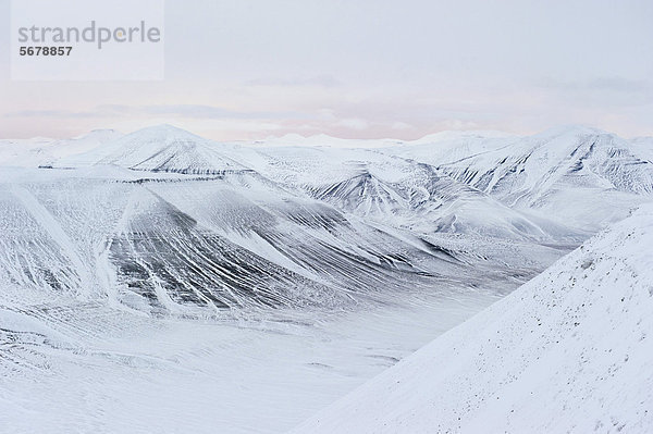 Pastellfarbenes Licht am Horizont über schneebedeckter Berglandschaft zu Beginn der Polarnacht  Spitzbergen  Svalbard  Norwegen  Europa