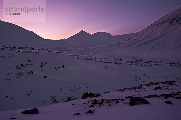 Lichtstimmung der Polarnacht  pinkfarbener Himmel vor schneebedeckter Kulisse einer steinigen Gletscherlandschaft  Spitzbergen  Svalbard  Norwegen  Europa