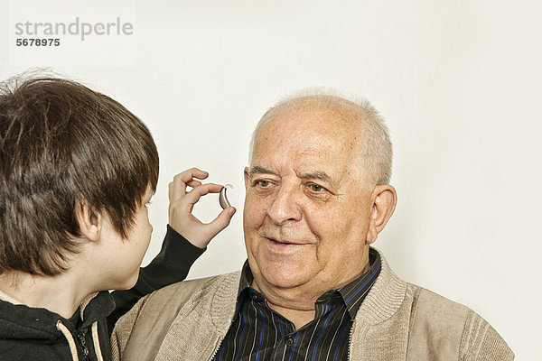 Enkelsohn gibt Großvater Hörgerät