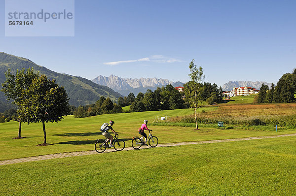 Paar mit Elektrofahrrädern vor dem Golfhotel Peternhof  zwischen Reit im Winkl  Chiemgau  Oberbayern  Bayern  Deutschland  und Kössen  Tirol  Österreich  Europa