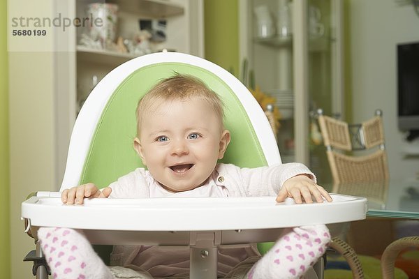 Fröhliches weibliches Baby sitzt im Hochstuhl