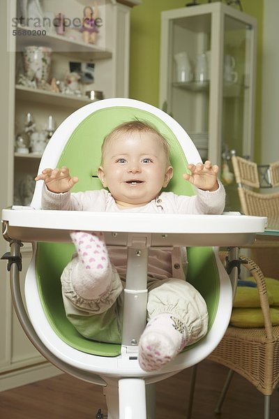 Fröhliches weibliches Baby sitzt im Hochstuhl