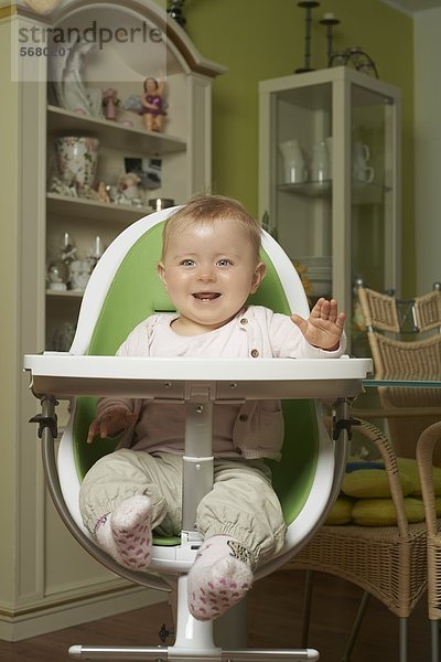 Fröhliches weibliches Baby sitzt im Hochstuhl