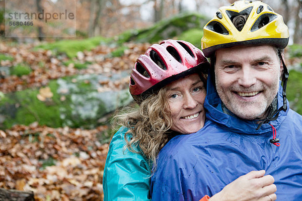 Portrait eines reifen Paares mit Fahrradhelmen im Wald
