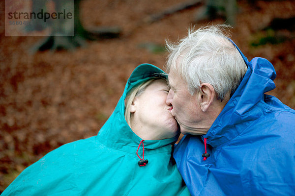 Senior Couple tragen Regenhose und küssen