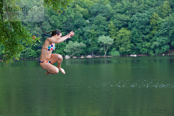 Mittlere erwachsene Frau  die in den Fluss springt.