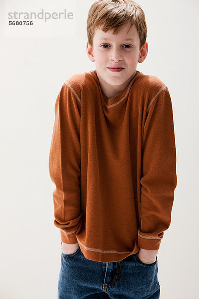 Junge in braunem Pullover mit Händen in den Taschen  Studioaufnahme