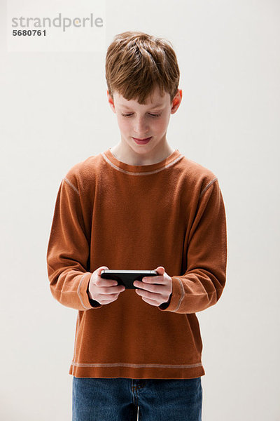 Junge in braunem Pullover spielt Handheld-Videospiel  Studioaufnahme