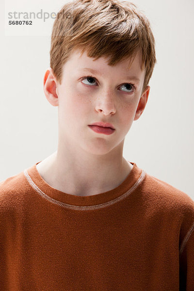 Junge in braunem Pullover mit rollenden Augen  Studioaufnahme