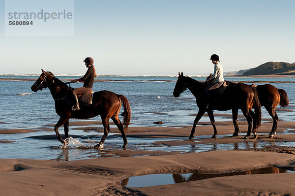 Zwei Frauen auf Pferden am Strand