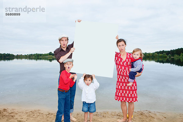 Familie am See  ein leeres Schild haltend