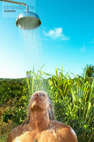 Mann genießt kühle Dusche im Freien