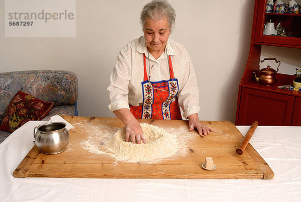 Ältere Frau beim Backen im Wohnzimmer