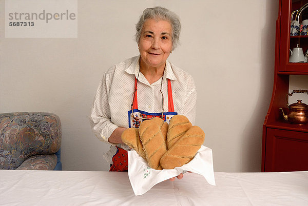 Ältere Frau beim Brotbacken im Wohnzimmer