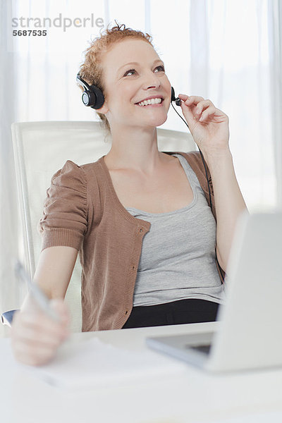 Geschäftsfrau mit Headset am Schreibtisch