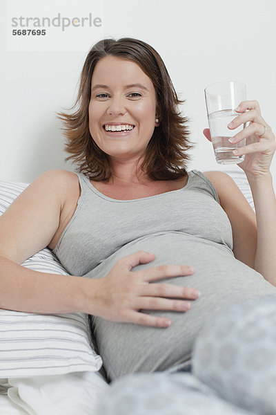 Frau mit schwangeren Bauch auf dem Bett