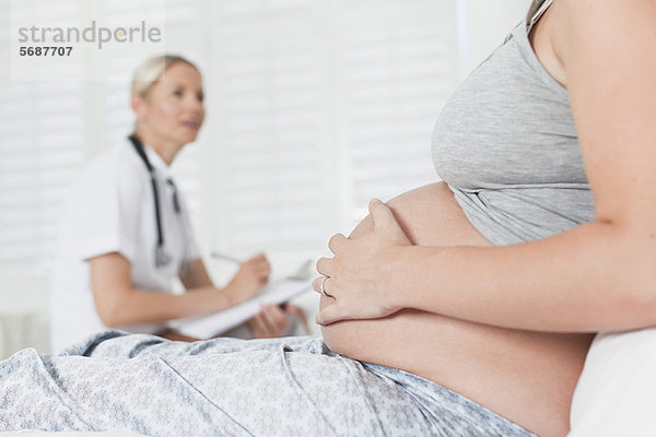 Arzt im Gespräch mit einer schwangeren Frau