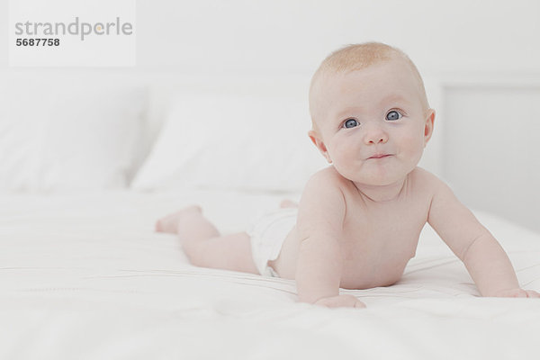 Lächelndes Baby auf dem Bett liegend