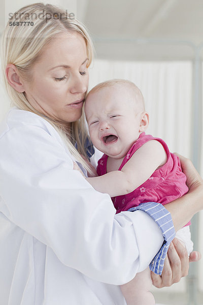 Doktor umarmt weinendes Baby