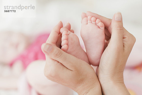 Hände von Müttern  die Babys Füße schröpfen