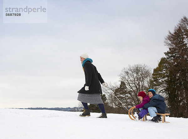Mutter zieht Kinder auf Schlitten im Schnee