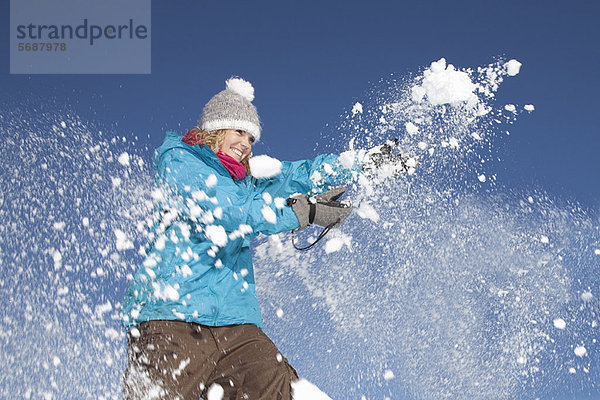 Frau spielt mit Schnee im Freien