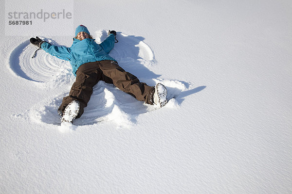 Frau macht Schneeengel auf dem Feld