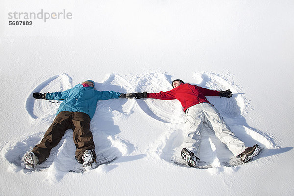 Paar macht Schnee-Engel im Freien