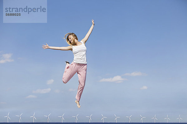 Frau springt vor Freude über Windkraftanlagen