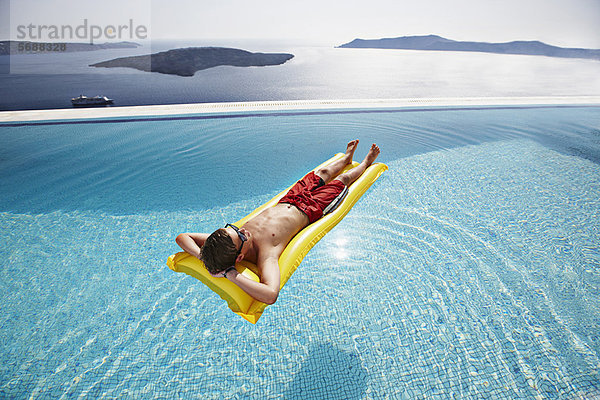 Teenager-Junge entspannt auf dem Floß im Pool