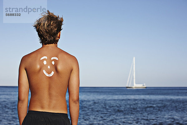 Junge mit Zeichnung in Sonnencreme auf dem Rücken