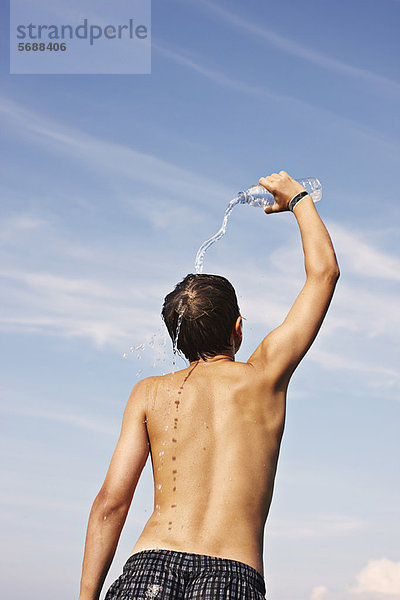 Teenager-Junge gießt Wasser auf sich selbst.