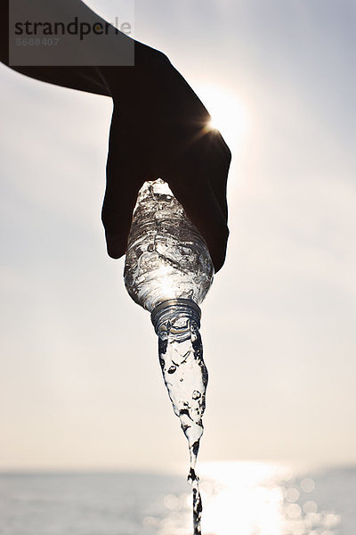 Teenager-Junge gießt Wasser aus der Flasche