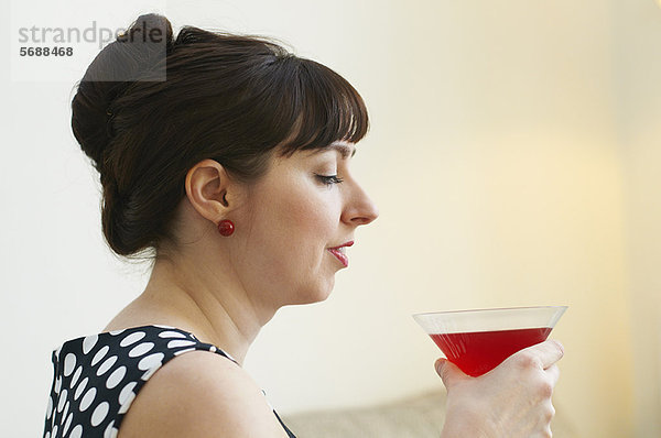 Frau trinkt Cocktail im Wohnzimmer