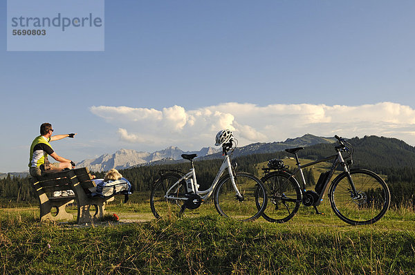 Paar mit Elektrofahrrädern bei Rast auf der Winklmoos-Alm  Reit im Winkl  Chiemgau  Oberbayern  Bayern  Deutschland  Europa