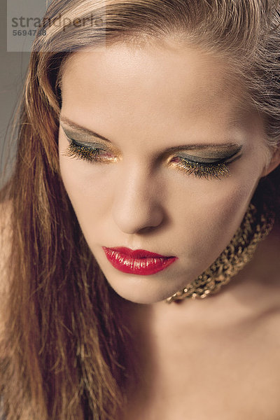 Junge Frau mit roten Lippen und goldenem Make-Up