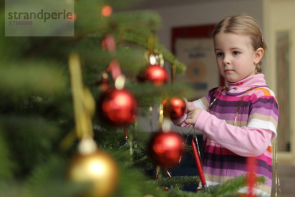 Mädchen schmückt Weihnachtsbaum