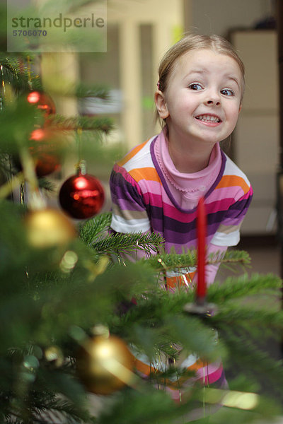 Mädchen schmückt Weihnachtsbaum