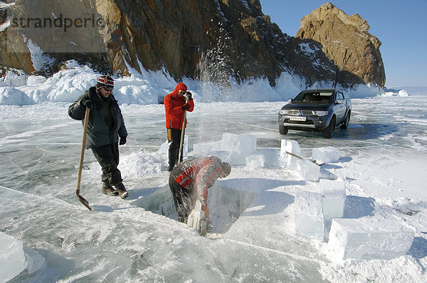 Mann sägt ein Loch ins Eis  Vorbereitungen fürs Eistauchen  Baikalsee  Insel Olchon  Sibirien  Russland  Eurasien