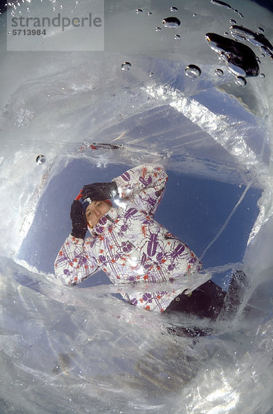 Frau schaut durch ein Eisloch  Baikalsee  Insel Olchon  Sibirien  Russland  Eurasien
