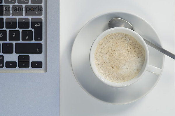 Laptop und Tasse Kaffee auf weißem Hintergrund