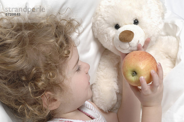Mädchen füttern Apfel an Teddybär