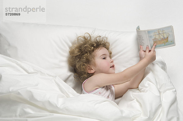 Mädchen auf dem Bett liegend mit Buch