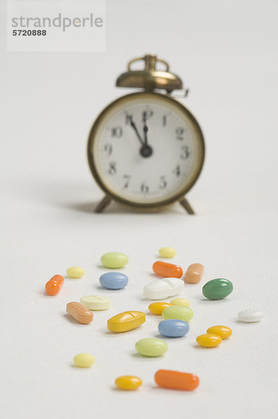 Wecker und Pillen auf weißem Hintergrund