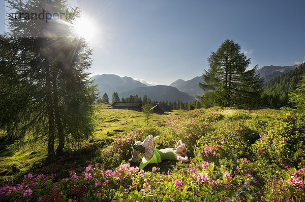 Österreich  Salzburger Land  Junge Frau auf der Alm liegend