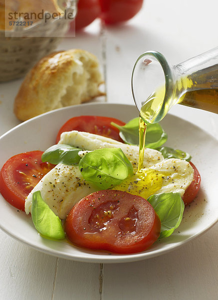 Olivenöl auf Caprese-Salat im Teller  Nahaufnahme