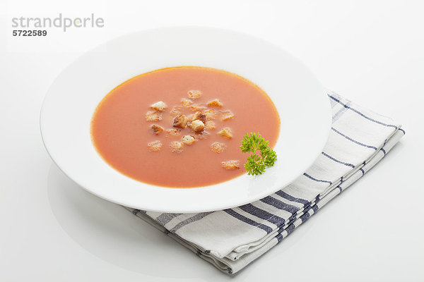 Tomatensuppe im Teller mit Serviette auf weißem Hintergrund