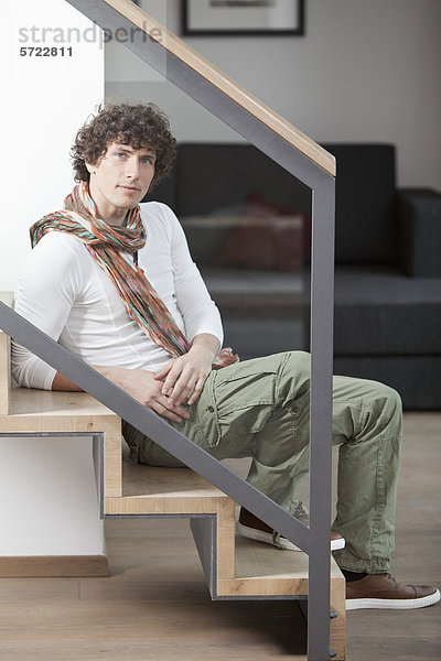Junger Mann auf der Treppe zu Hause sitzend  Porträt